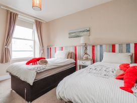 A bedroom with two beds, a lamp and curtains at The View in Criccieth