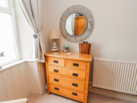 A chest of drawers with a mirror and lamp in a bedroom at The View in Criccieth