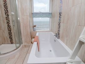A bathroom with a bathtub and shower overlooking the sea at The View in Criccieth