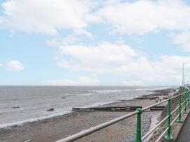 A beach with a railing and cloudy sky at The View in Criccieth
