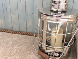 A lantern with a candle and shells on sand at The View in Criccieth