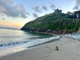 A beach with water and a castle on a hill at The View in Criccieth