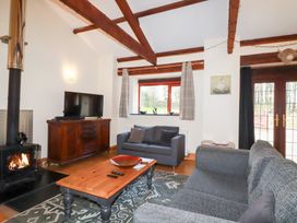 A living room with a wood stove and television at Kingfisher Barn in East Taphouse