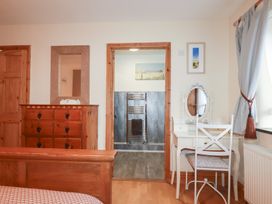 A bedroom featuring a dresser, mirror, and towel radiator at Kingfisher Barn in East Taphouse