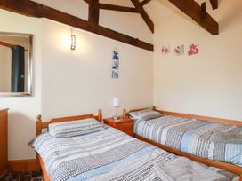 A bedroom with two beds and a mirror at Kingfisher Barn in East Taphouse