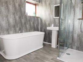 A bathroom with a bathtub, sink, shower, and mirror at Kingfisher Barn in East Taphouse