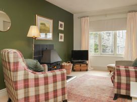 A living room with an armchair, fireplace, and television at Gable End in Coniston near Hawkshead