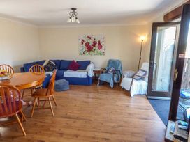 A living room with a blue sofa and wooden dining table with chairs at Ysgubor - Barn in Betws Yn Rhos