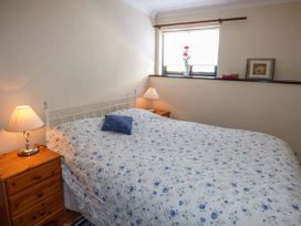 A bedroom with a bed covered in floral bedding and two bedside tables with lamps at Ysgubor - Barn in Betws Yn Rhos
