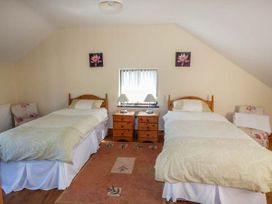 A bedroom with two single beds separated by two wooden nightstands with lamps at Ysgubor - Barn in Betws Yn Rhos