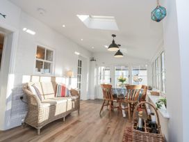 A conservatory with a dining table and wicker sofa at Croft View Fylingthorpe near Robin Hood's Bay