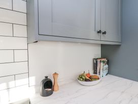 A kitchen with cabinets, a bowl of fruit, and books at Croft View in Fylingthorpe near Robin Hood's Bay
