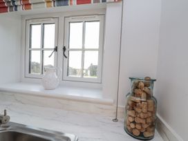A kitchen with a sink, pitcher, cork jar, and windows at Croft View in Fylingthorpe near Robin Hood's Bay