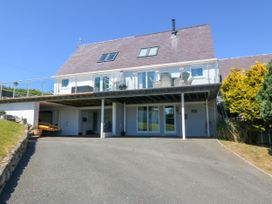 A house with a sloped roof and glass balcony overlooking a driveway at St Tudwals View in Abersoch