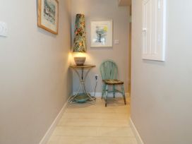 A hallway with a small table holding a lamp and a worn wooden chair at St Tudwals View in Abersoch