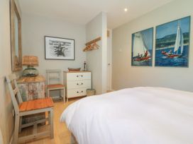 A bedroom with two chairs a chest of drawers a lamp and sailing pictures on the walls at St Tudwals View in Abersoch