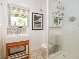 A bathroom with a sink on a wooden stand a toilet and a glass shower enclosure at St Tudwals View in Abersoch