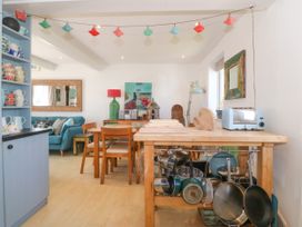 A kitchen and dining area with wooden table and chairs pots and pans hanging under wooden island at St Tudwals View in Abersoch