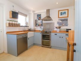 A kitchen with blue cabinets wooden countertops a dishwasher a double oven and a farmhouse sink at St Tudwals View in Abersoch