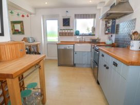 A kitchen with wooden countertops blue cabinets a dishwasher and a farmhouse sink at St Tudwals View in Abersoch