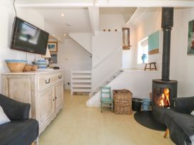 A living room with a wood burning stove television and vintage cabinet at St Tudwals View in Abersoch