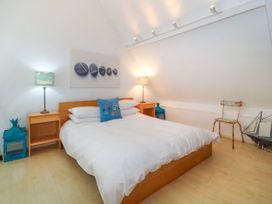 A bedroom with a double bed two bedside tables with lamps a chair and decorative items at St Tudwals View in Abersoch