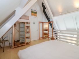 A bedroom with a bed a wardrobe a folding mirror and a white railing at St Tudwals View in Abersoch