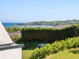 A garden with bushes and a lawn overlooking the sea and hills at St Tudwals View in Abersoch