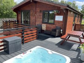 An outdoor area with a deck, spa, and seating at Wildcat Lodge in Newtonmore