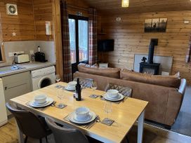 A living room with a dining table and kitchen appliances at Wildcat Lodge in Newtonmore
