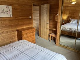 A bedroom with a bed, dresser, and mirror at Wildcat Lodge in Newtonmore