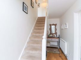 A hallway with a staircase and a table at Fernlea in Morfa Nefyn
