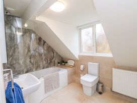 A bathroom with a bathtub, toilet, sink, and window at Fernlea in Morfa Nefyn