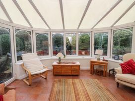 A conservatory with seating and a table at Fernlea in Morfa Nefyn