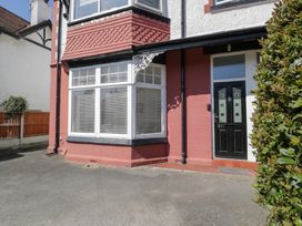 Exterior view of a red brick house with a black front door bay window and a hedge at Hafan Y Mor in Rhos-on-Sea