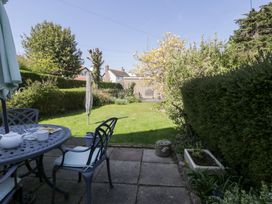 A garden with patio furniture a round table with teapot and cup a folded umbrella and hedges at Hafan Y Mor in Rhos-on-Sea
