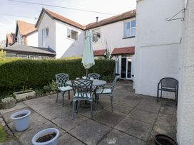 An outdoor patio with a round table with chairs and an umbrella and some empty flower pots at Hafan Y Mor in Rhos-on-Sea