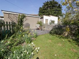 A garden with grass and flowers a small seating area and buildings in the background at Hafan Y Mor in Rhos-on-Sea
