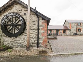 Stone buildings with black and red trim and a large black water wheel with the words Felin Carrog Mill on the side at The Dairy Carrog near Corwen