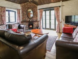 A living room with leather sofas a coffee table a fireplace a television and floral curtains at The Dairy Carrog near Corwen