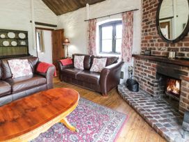 A living room with two leather sofas floral cushions a wooden coffee table a fireplace and a rug at The Dairy in Carrog near Corwen