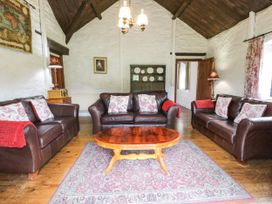 A living room with three brown leather sofas a wooden coffee table and a rug at The Dairy in Carrog near Corwen