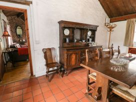 A dining room with a wooden table and chairs a wooden sideboard and a coat stand at The Dairy in Carrog near Corwen