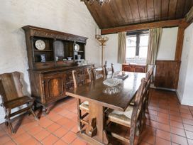 A dining room with wooden table and chairs and an antique cabinet with ceramic plates at The Dairy in Carrog near Corwen