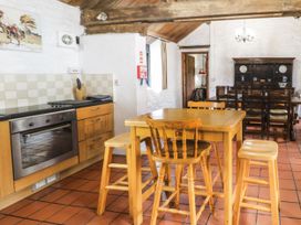A kitchen with a wooden table and chairs and an oven with cabinets at The Dairy in Carrog near Corwen