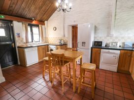 A kitchen with wooden table and stools dishwasher fridge microwave and toaster at The Dairy in Carrog near Corwen