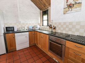 A kitchen with wooden cabinets a microwave toaster oven and a window at The Dairy in Carrog near Corwen