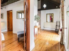 A hallway with wooden floors a small round table with a plant a hanging light and mirrors at The Dairy in Carrog near Corwen