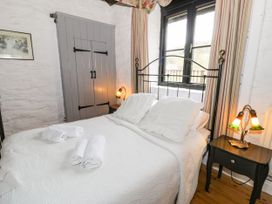 A bedroom with a bed covered in white bedding and towels on top by a window with striped curtains at The Dairy in Carrog near Corwen