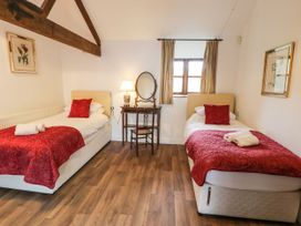 A bedroom with two single beds a wooden dressing table and chair and framed pictures on walls at The Dairy in Carrog near Corwen